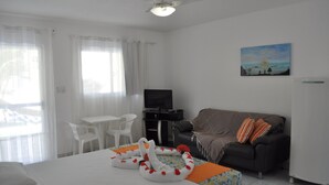 A hotel room with a bed, a sofa, a TV, a desk, and a painting on the wall. - Pousada Jóia Rara (Ipojuca)