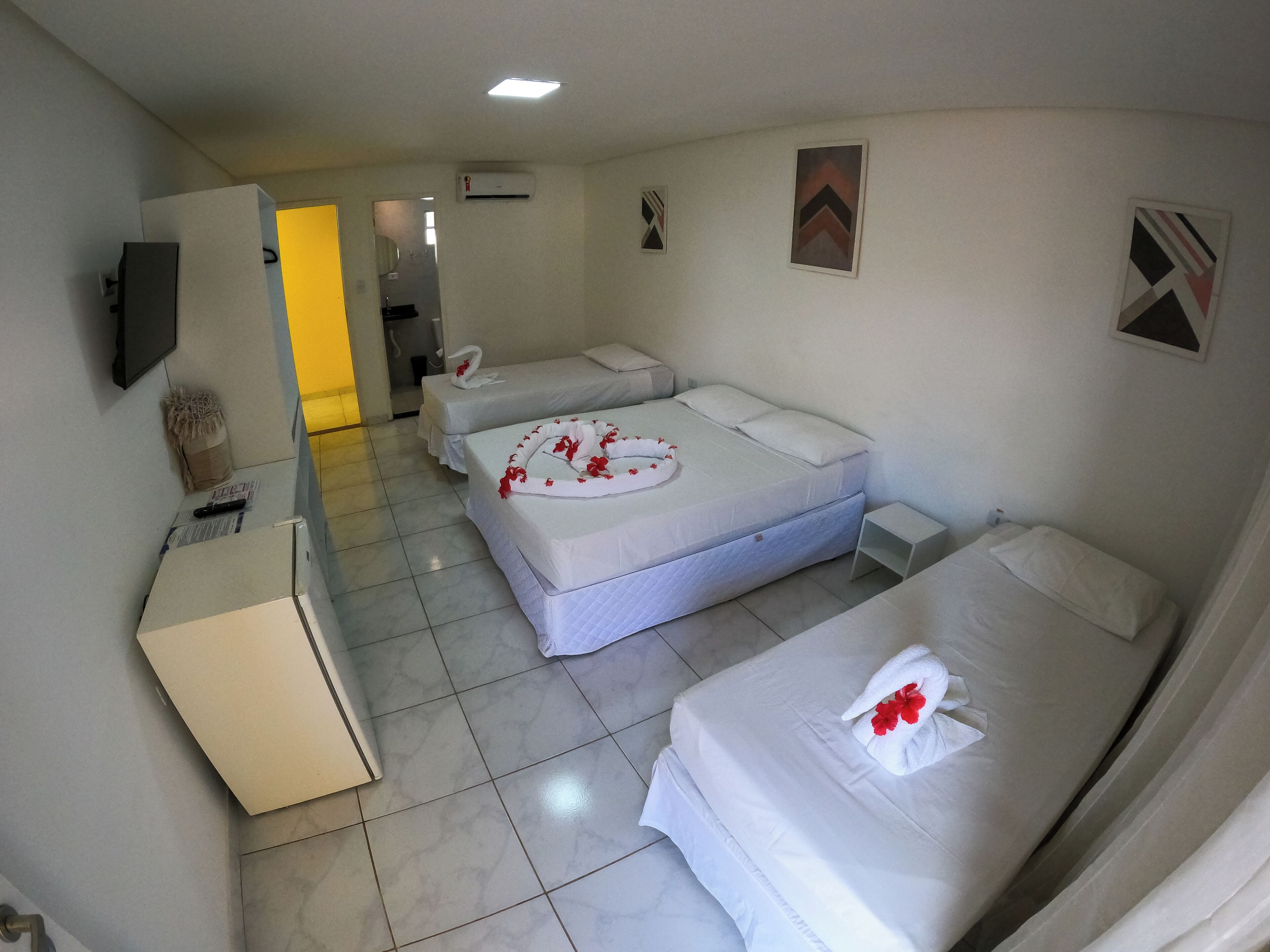 Une chambre d’hôtel avec deux lits, un bureau, un téléviseur à écran plat et une salle de bain visible au fond.