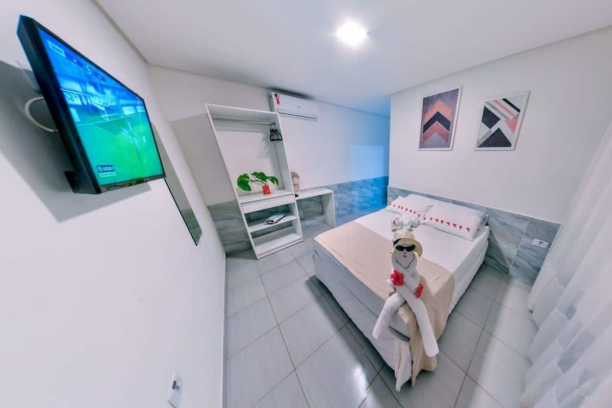 A modern hotel room with a bed, a TV, a wardrobe, and a bathroom.