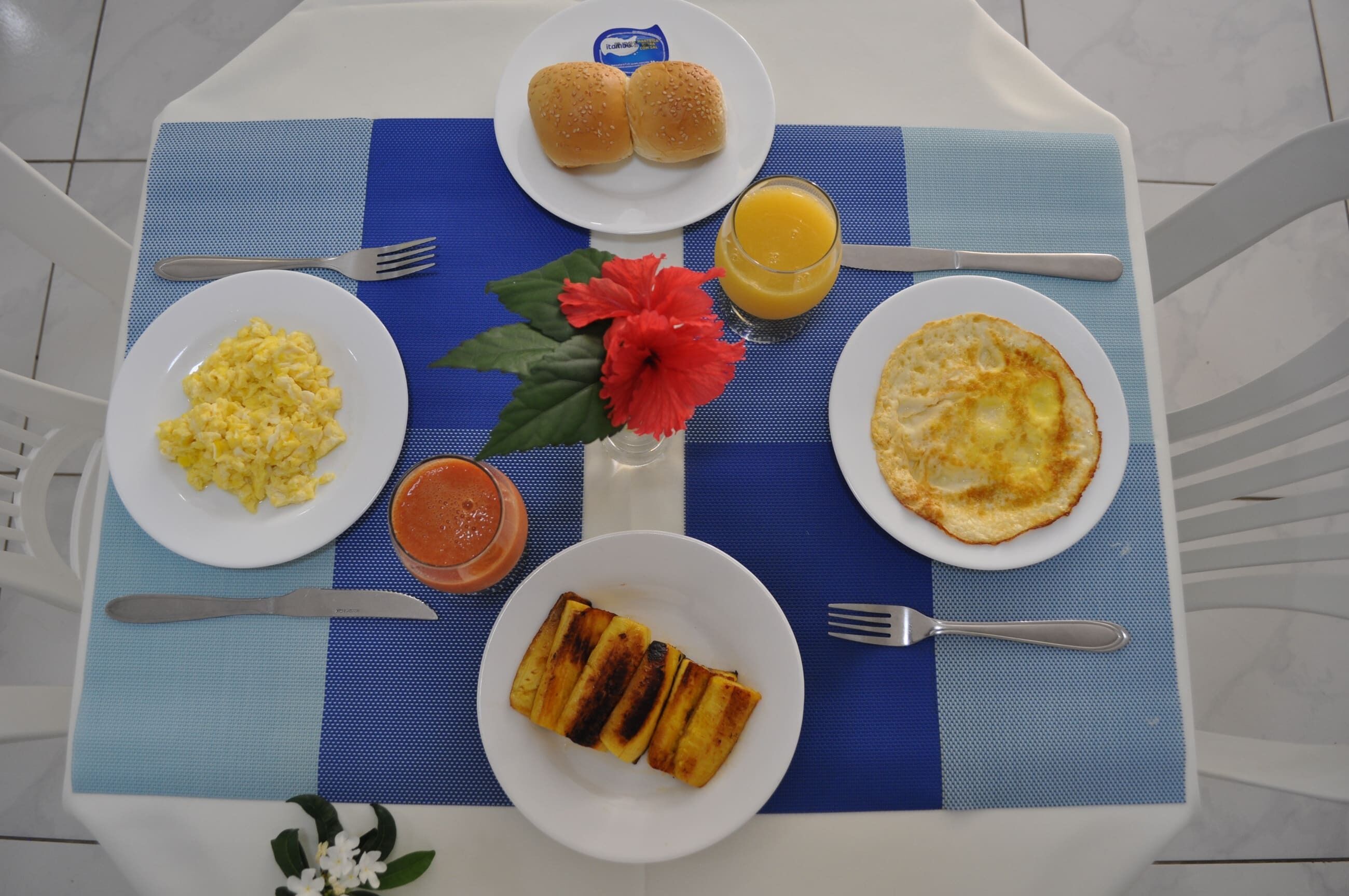 Una tavola imbandita per la colazione con uova strapazzate, pane tostato e insalata di frutta.