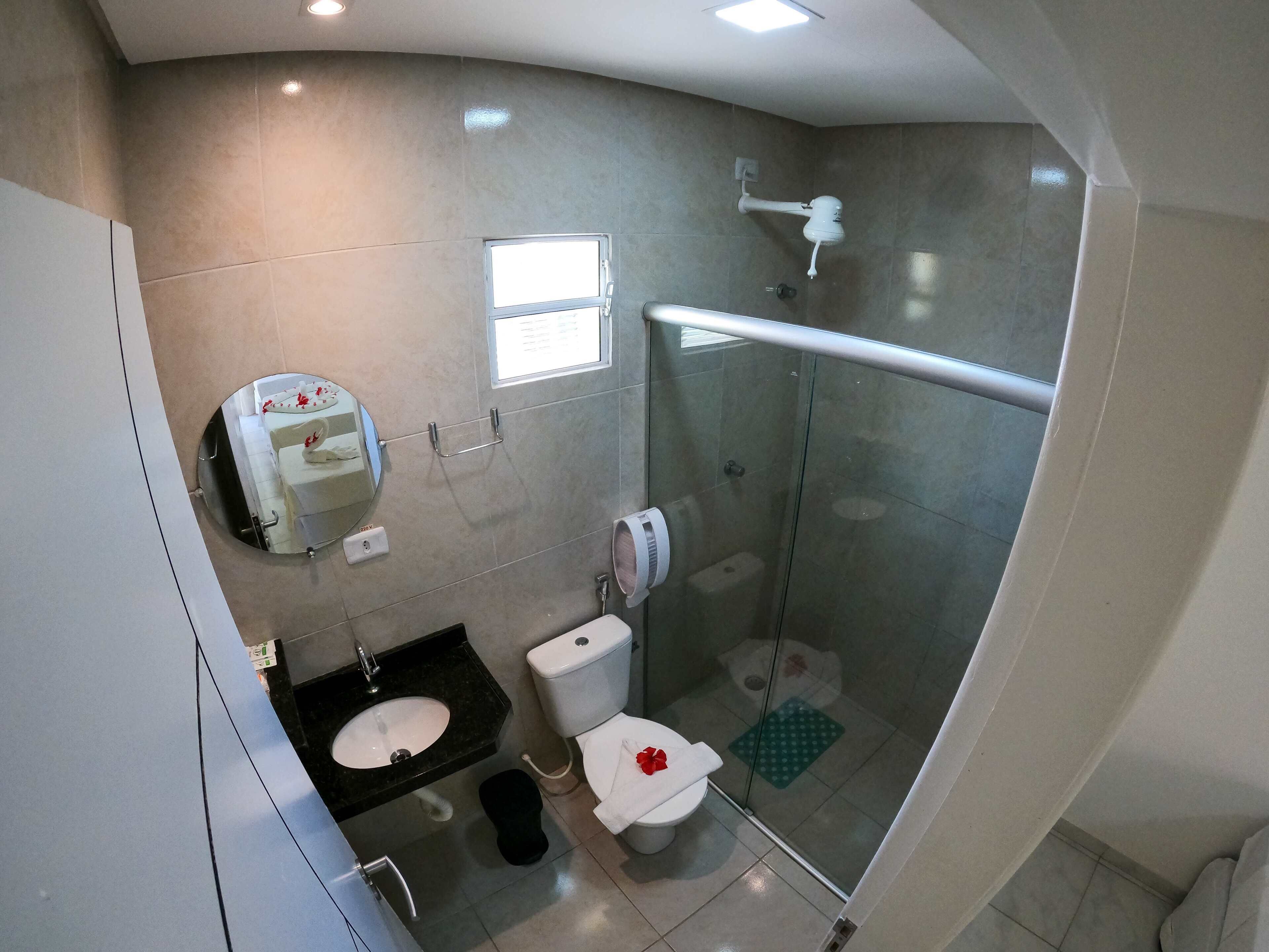 Une salle de bain moderne avec une douche à parois de verre, des toilettes, un lavabo et un miroir.