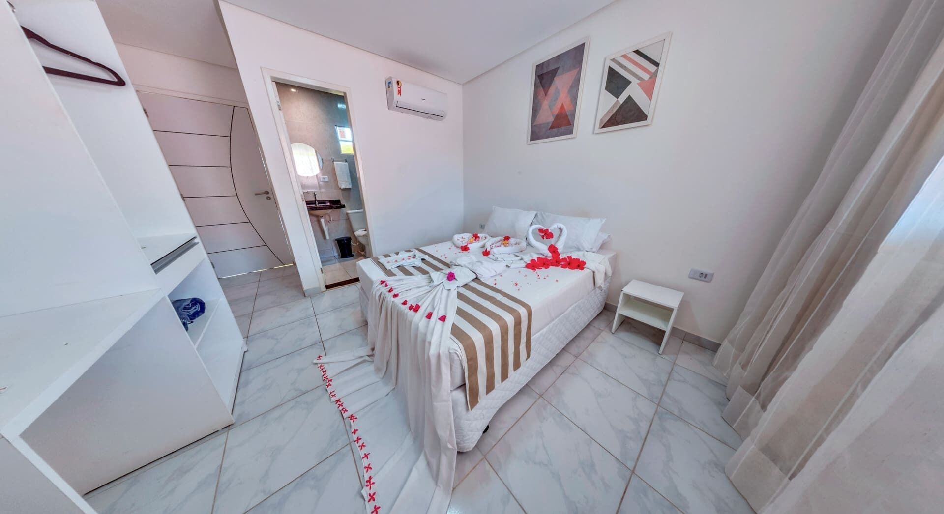 Una habitación de hotel con cama, una mesita de noche, armario y aire acondicionado.