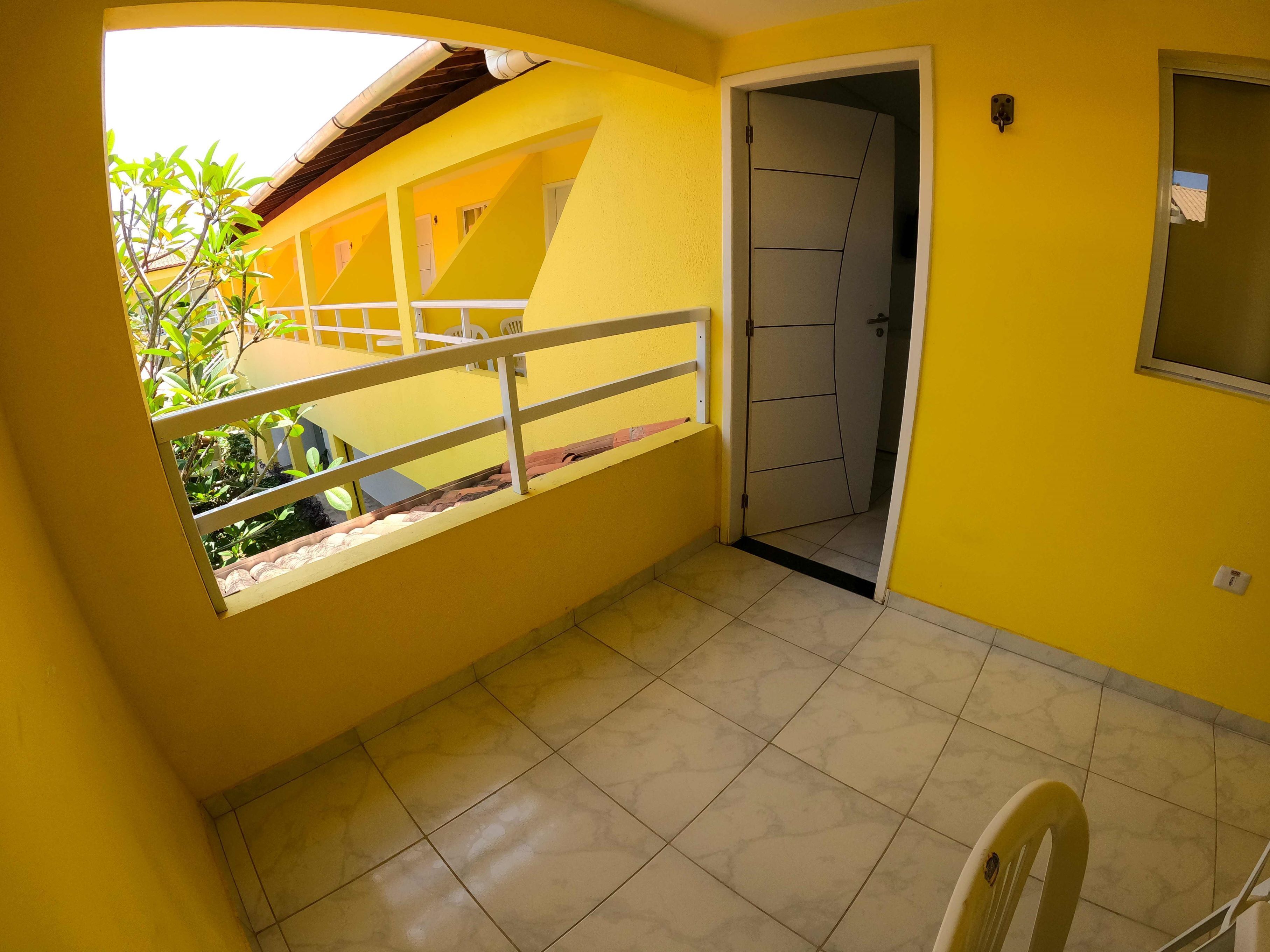 A yellow interior with a balcony, a door, and a window.