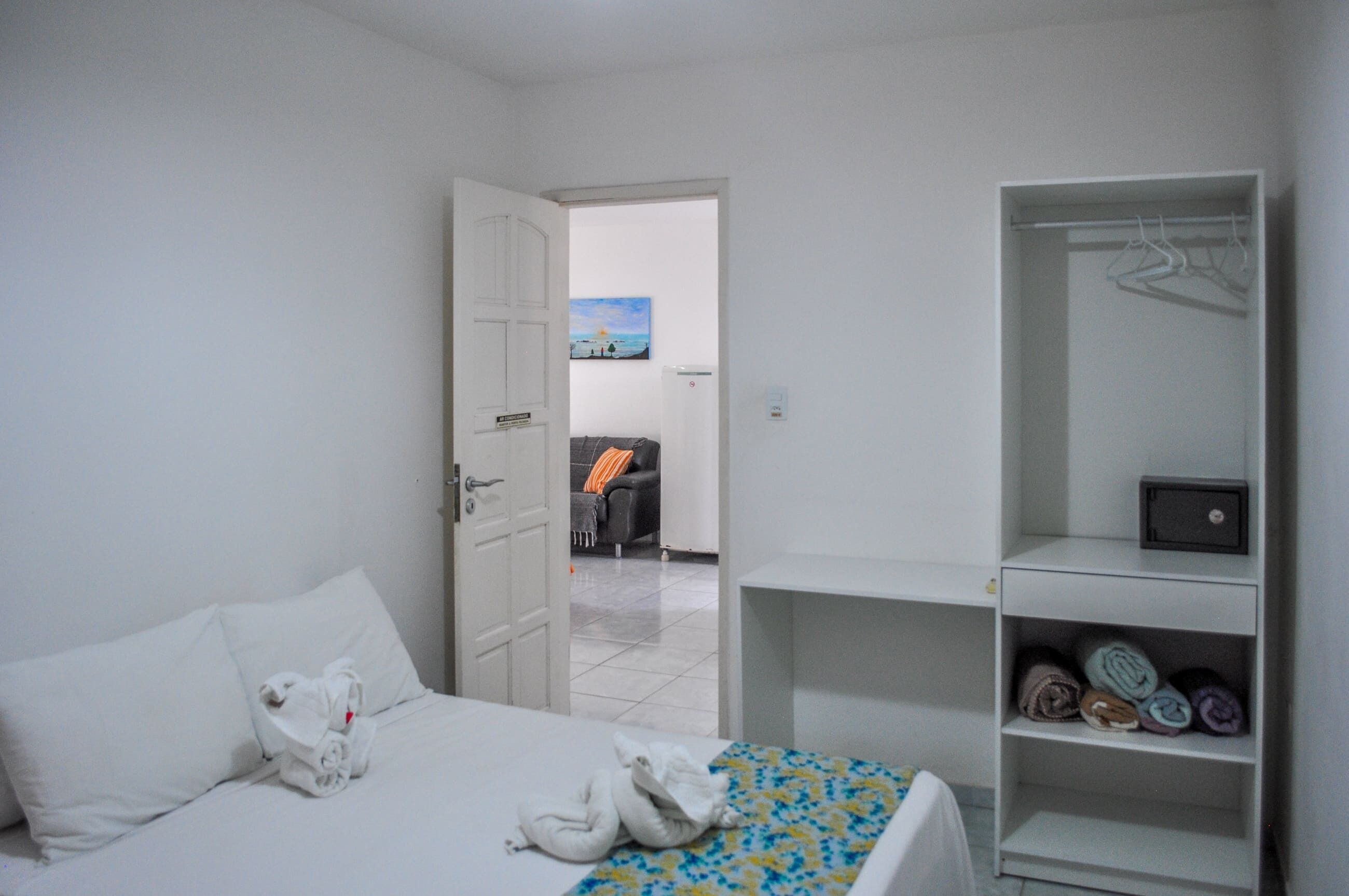 A hotel room with a bed, a wardrobe, and a view of a balcony with a painting.