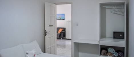 A hotel room with a bed, a wardrobe, and a view of a balcony with a painting.