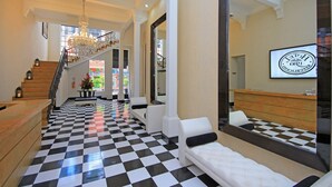 A hotel lobby with a checkered floor, a staircase, a chandelier, and a reception desk. - Hotel Republicano 1910 (Girardot)