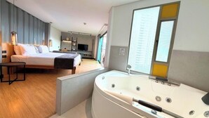 A modern hotel room with a large bed, a separate seating area, a TV, and a large bathtub. - Hotel Casa Victoria Medellín (Medellín)