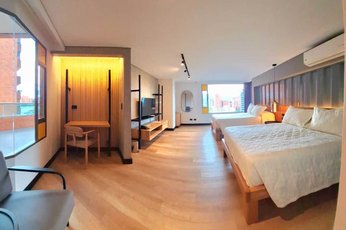 A modern hotel room with a large bed, a desk, and a TV.