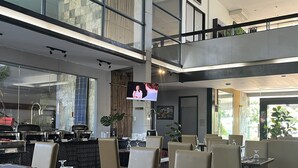 A modern restaurant with high ceilings, large windows, and a mezzanine level. - Technopark Hotel (Santa Rosa)