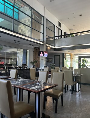 A modern restaurant with high ceilings, large windows, and a mezzanine level. - Technopark Hotel (Santa Rosa)