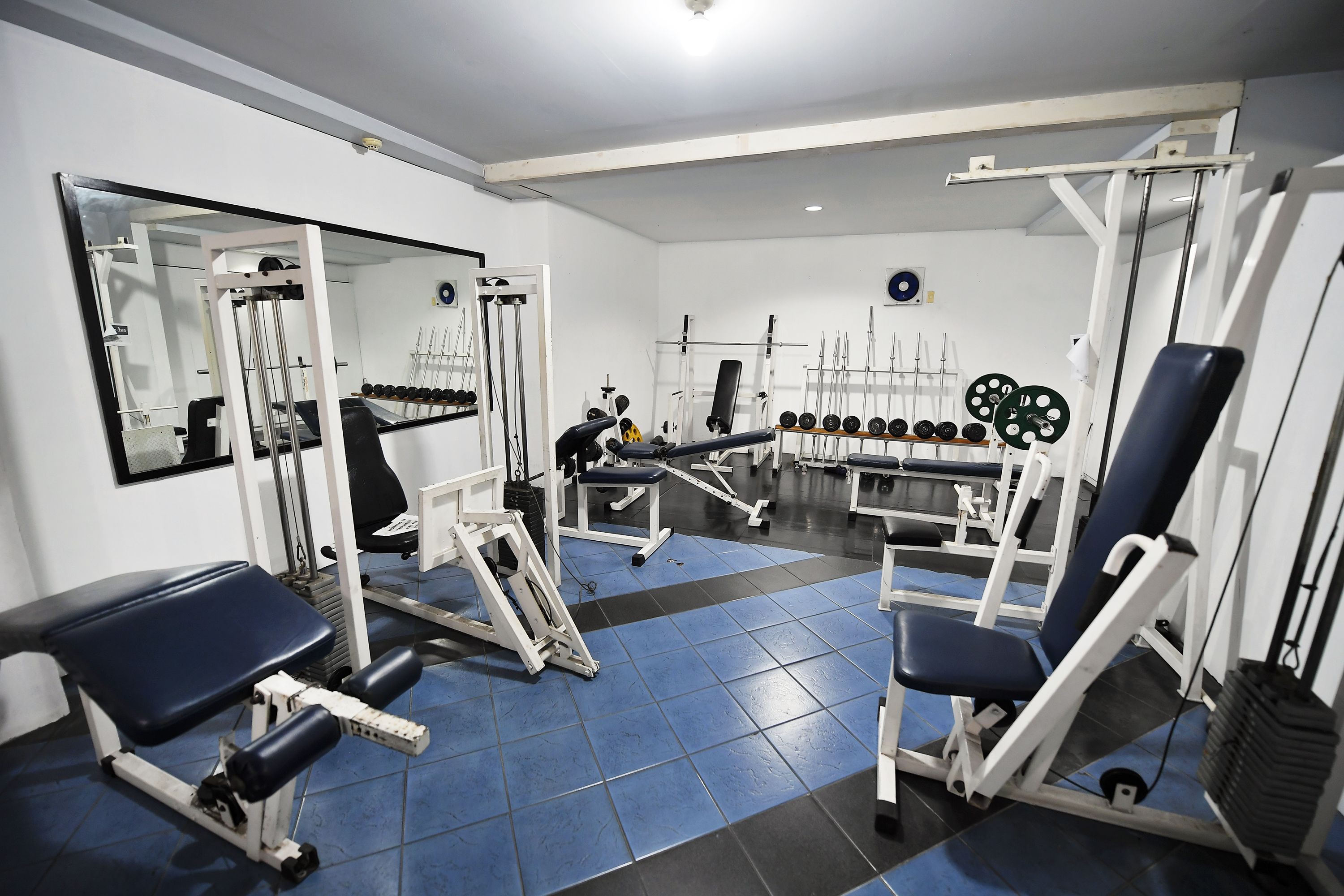 A gym with various exercise equipment, including benches, weight machines, and dumbbells.