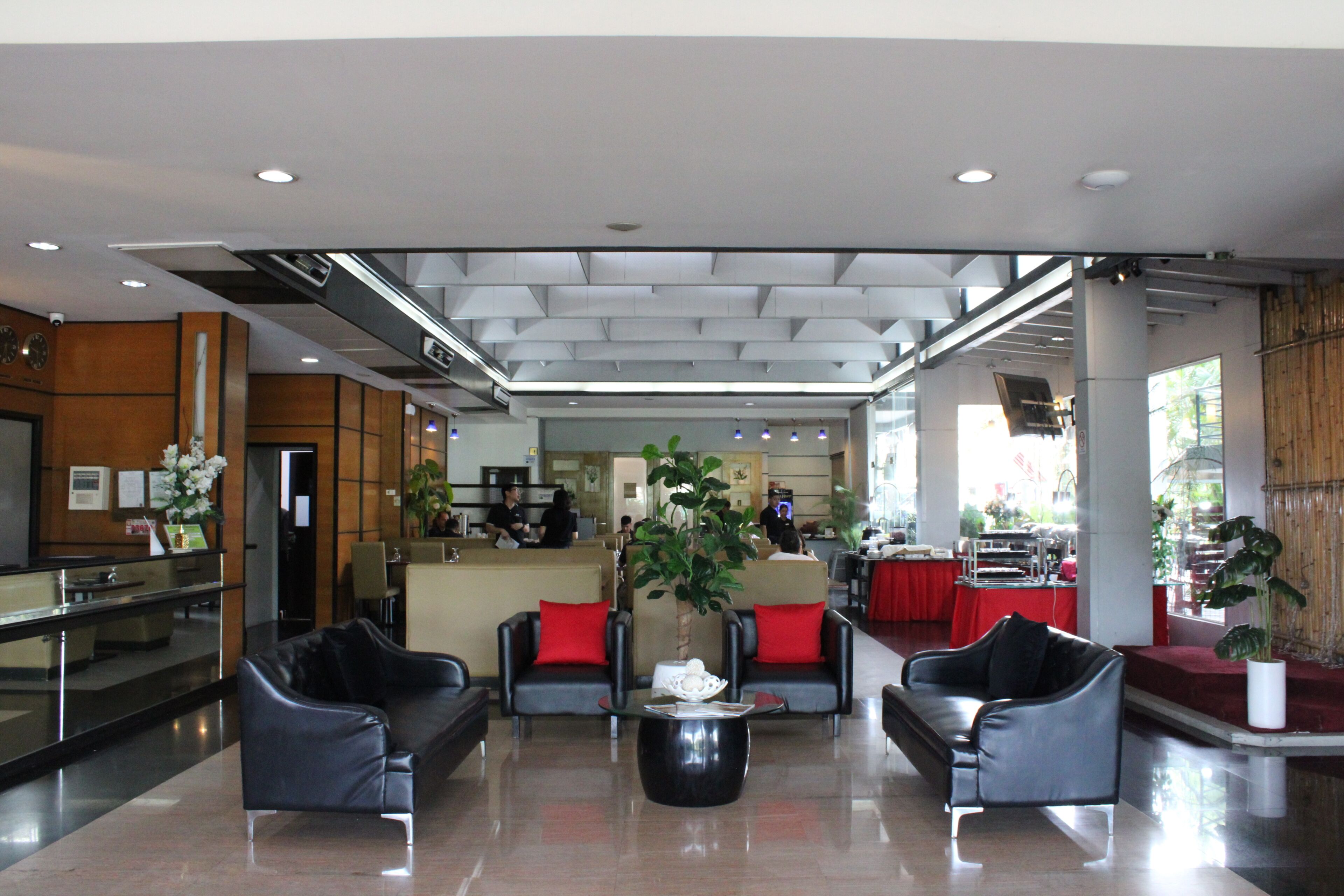 A hotel lobby with seating, a reception desk, and a kitchen area in the background.