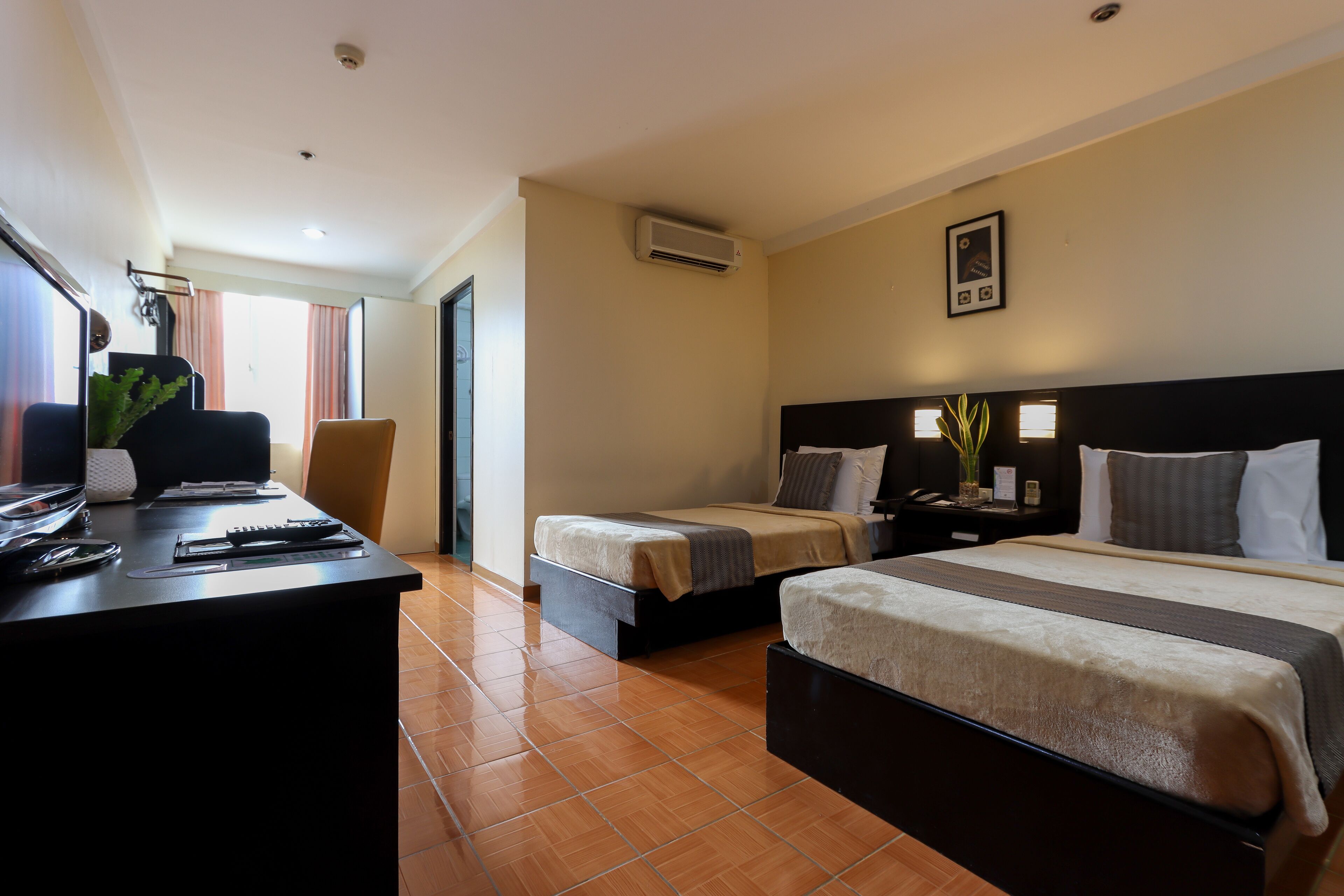 A hotel room with two beds, a desk, and a chair.