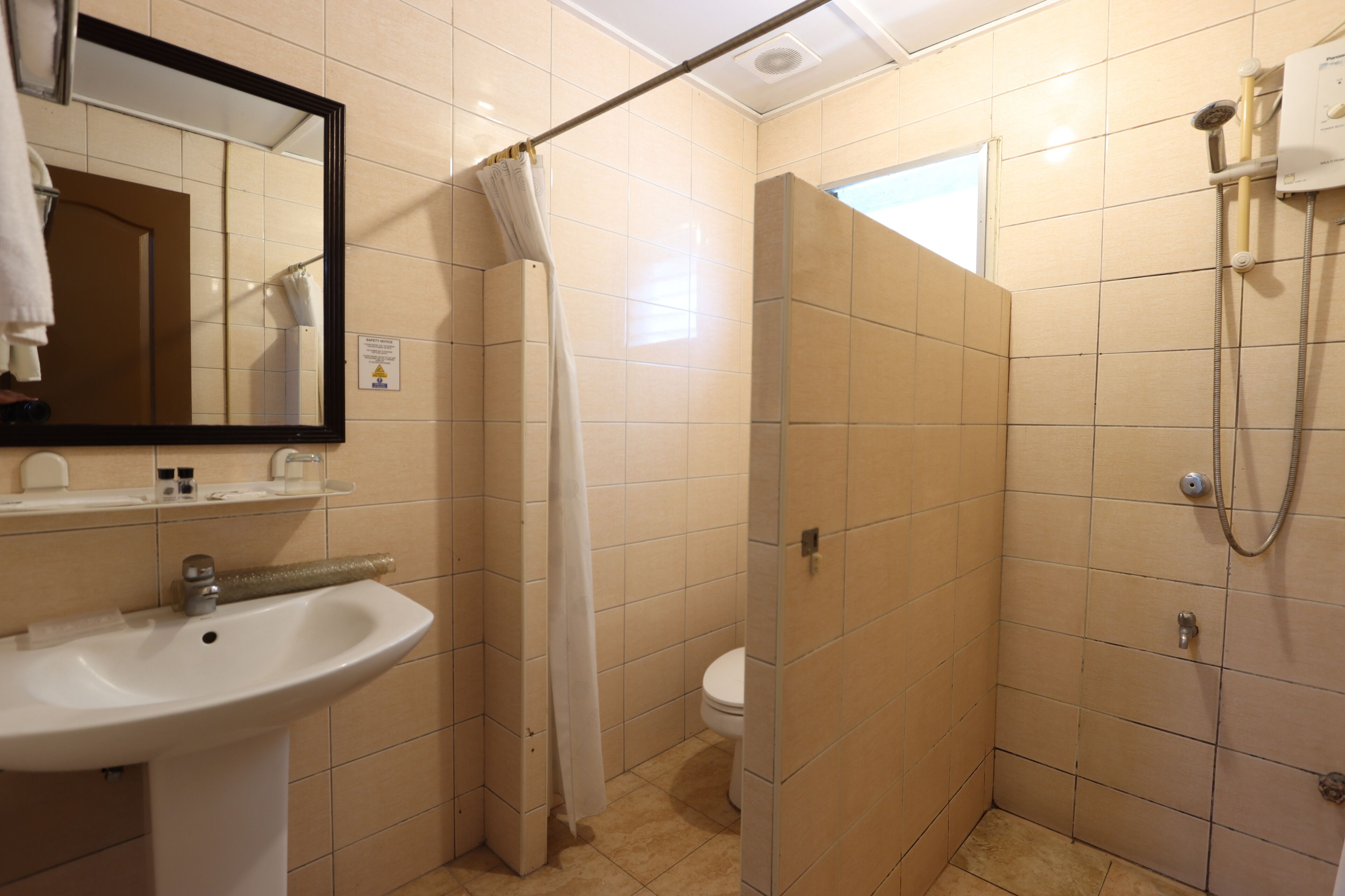 Une salle de bain équipée d’un lavabo, d’un miroir, d’une douche et de toilettes.