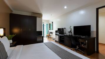 Una habitación de hotel con cama, escritorio con computadora, televisor y armario.