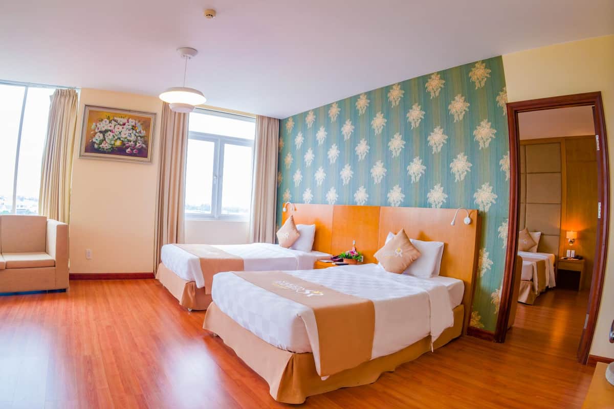 A hotel room with two beds, a sofa, and a large window.