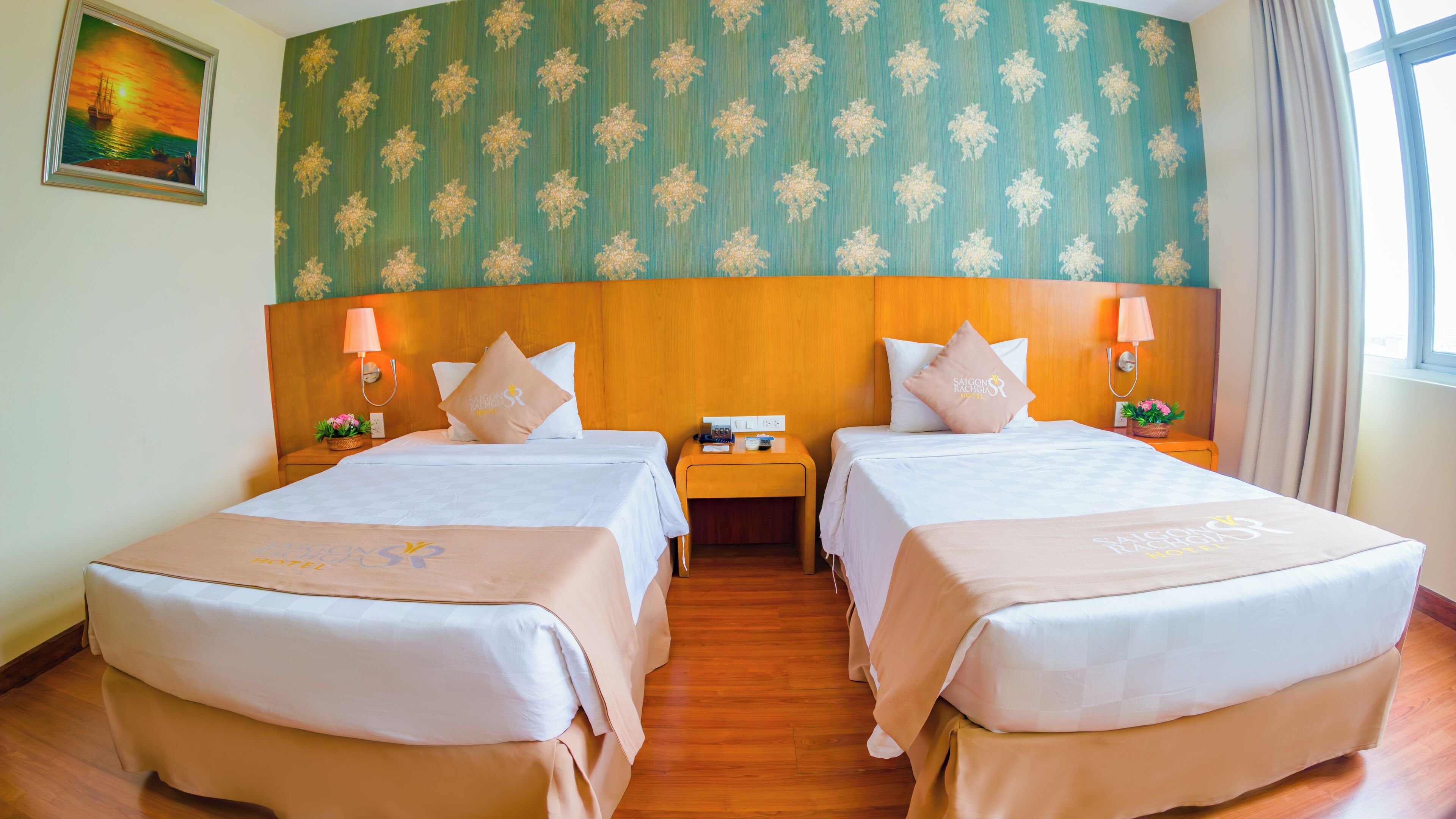 Une chambre d’hôtel avec deux lits, une tête de lit en bois, un papier peint à motifs floraux et un tableau au mur.