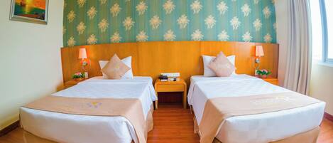 Une chambre d’hôtel avec deux lits, une tête de lit en bois, un papier peint à motifs floraux et un tableau au mur.