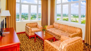 A hotel room with a large window, two sofas, a small table, and a TV. - Sai Gon Rach Gia Hotel (Rach Gia)