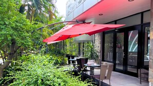 An outdoor patio with tables and chairs, surrounded by greenery. - Paseo Premiere Hotel (Santa Rosa)