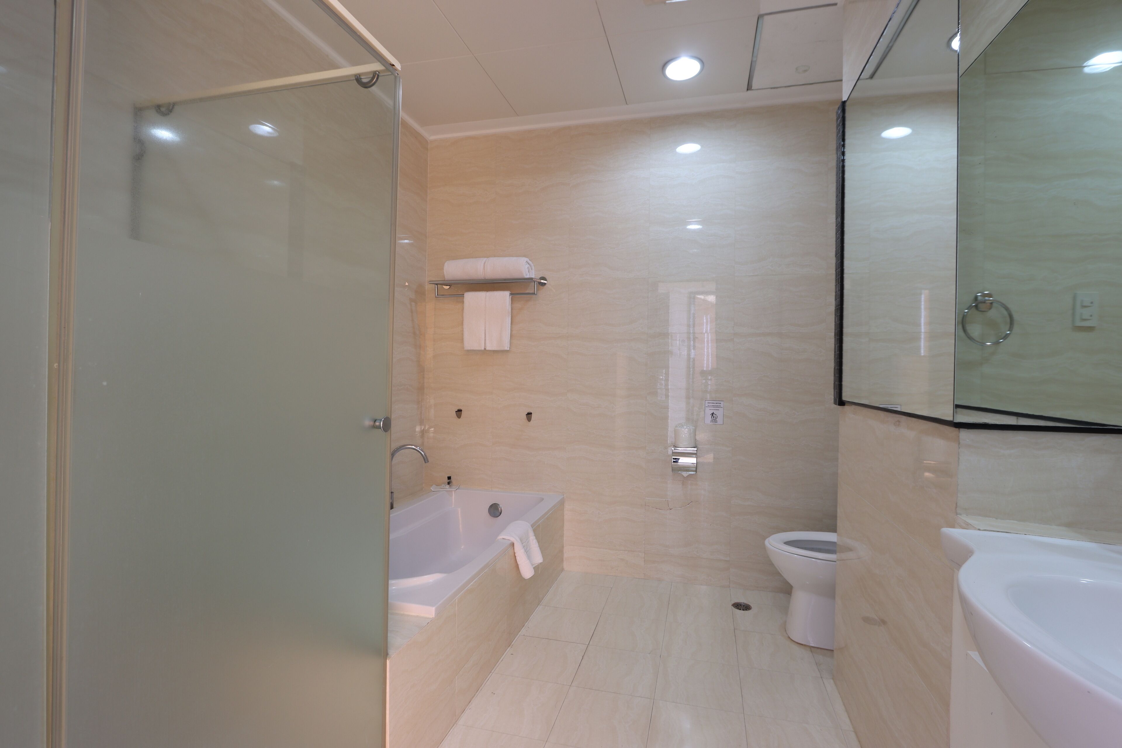 Een moderne badkamer met een douchecabine van glas, een badkuip, een toilet en een grote spiegel.