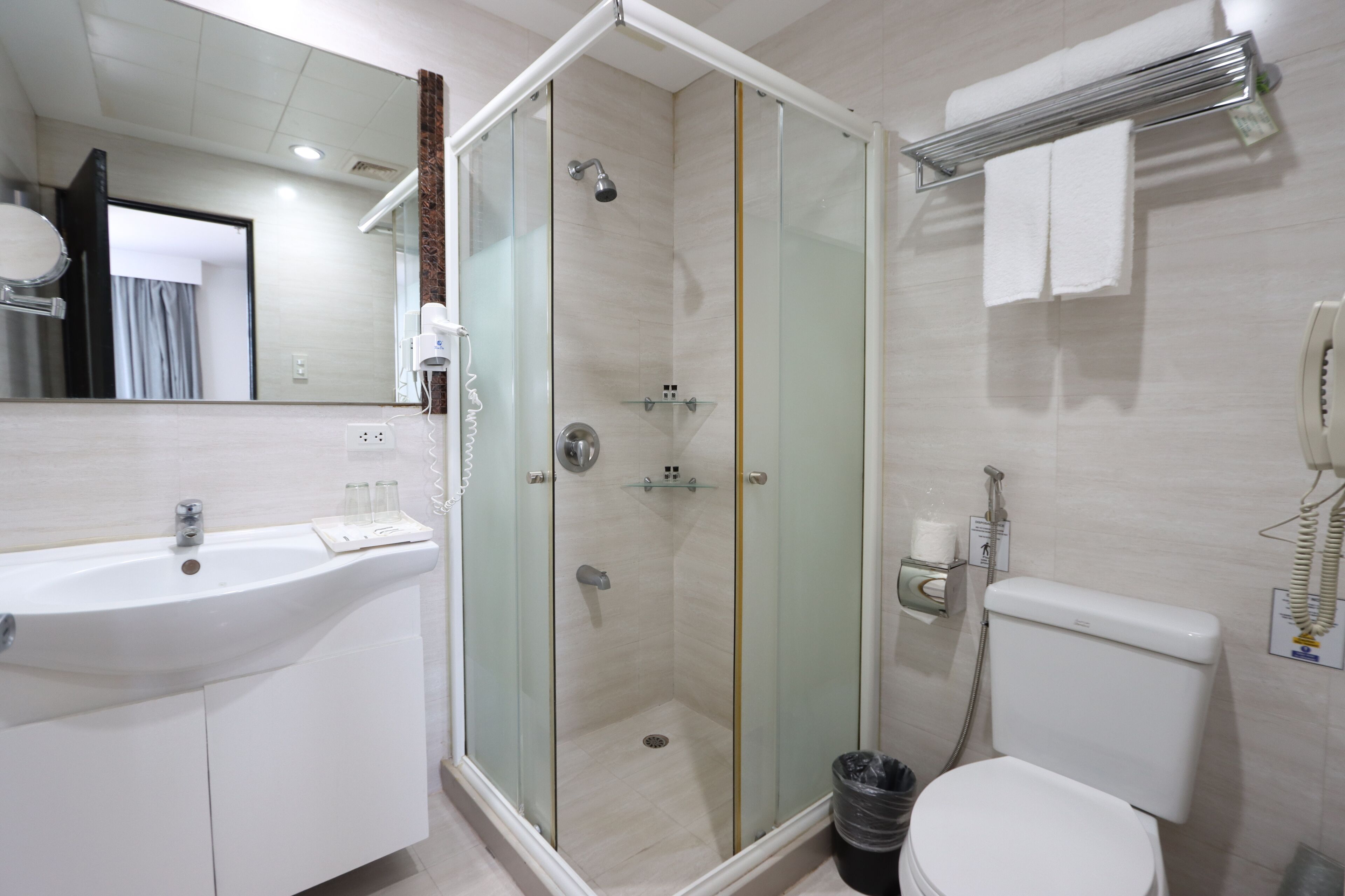 A modern bathroom with a glass-enclosed shower, a white sink, and a toilet.