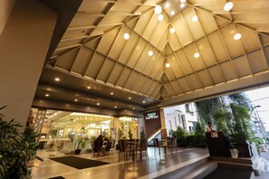 A hotel lobby with a modern design, featuring a large open space with seating and a reception desk. - Paseo Premiere Hotel (Santa Rosa)