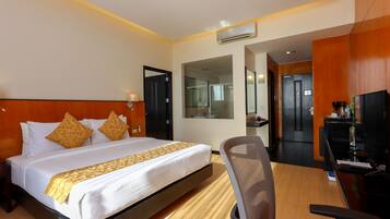 A hotel room with a large bed, a desk with a chair, a TV, and a mirror.
