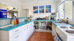 Cozinha com armários brancos, bancada azul, fogão, micro-ondas e três quadros na parede.
