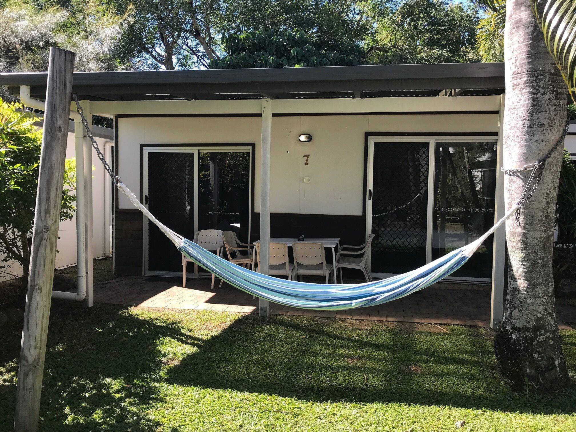 Un espacio al aire libre cubierto con una hamaca, una mesa y sillas.