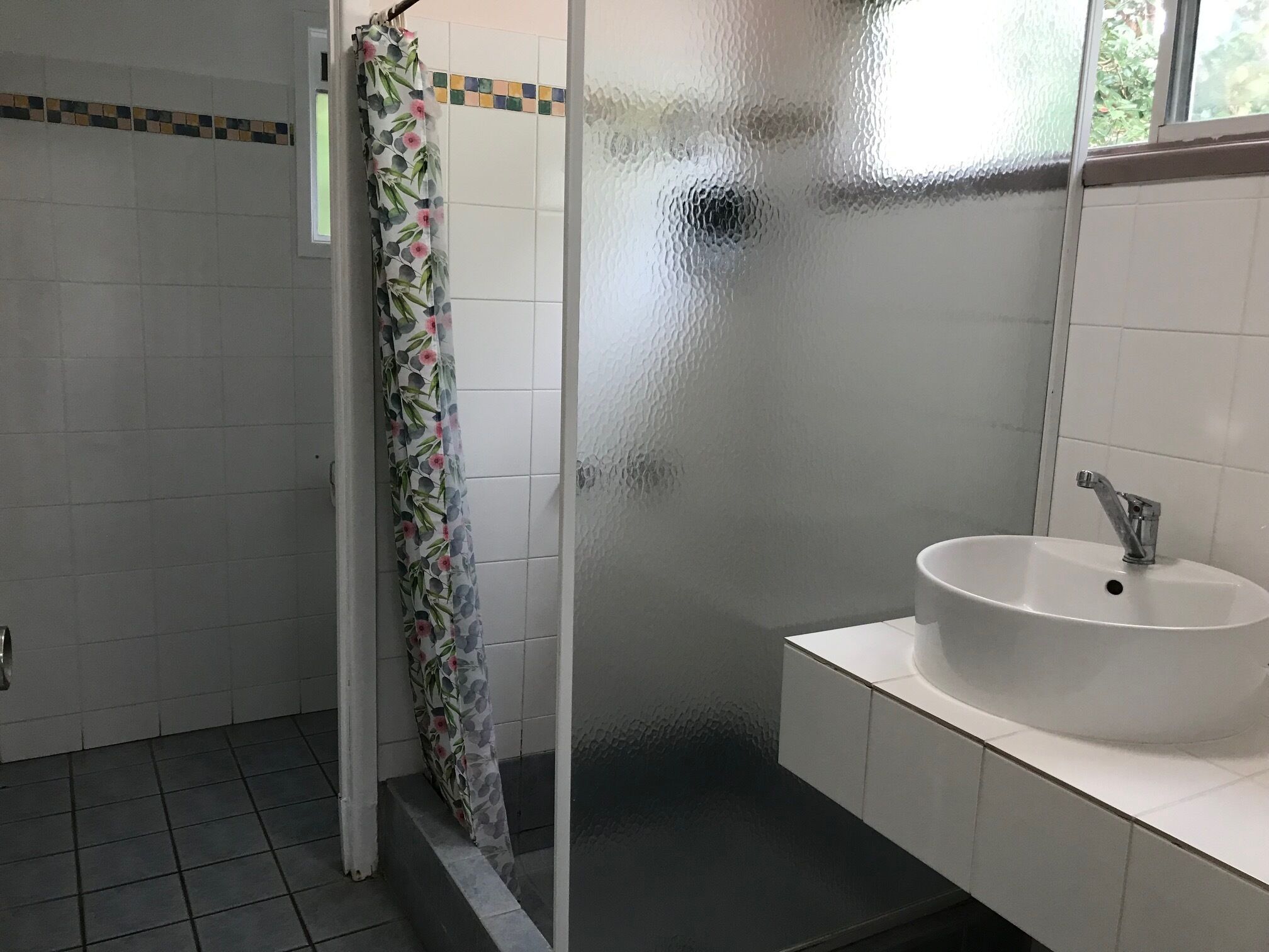 Une salle de bain avec une douche, un lavabo et des murs carrelés.