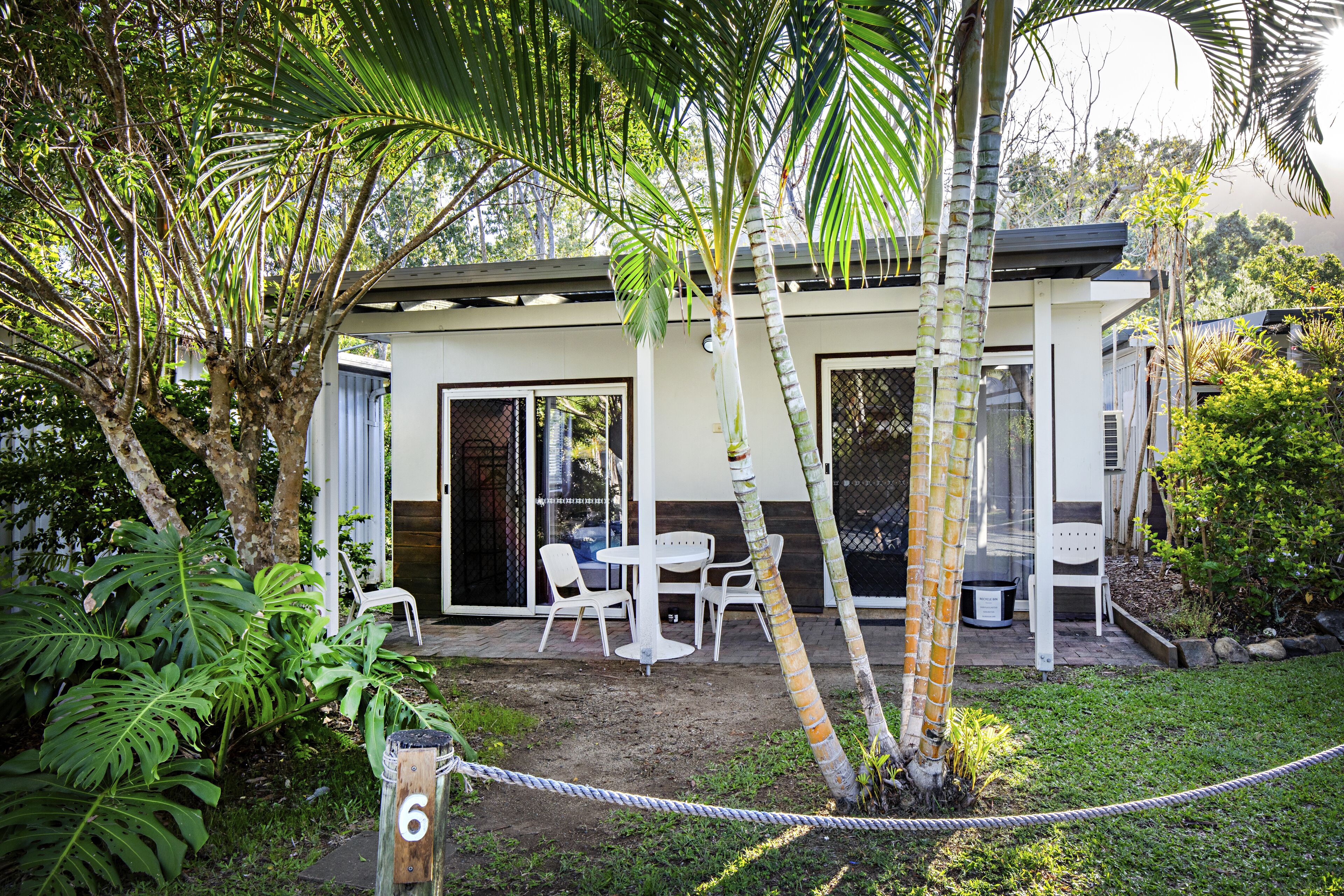 Una casa con patio, muebles blancos y un letrero con el número 6.