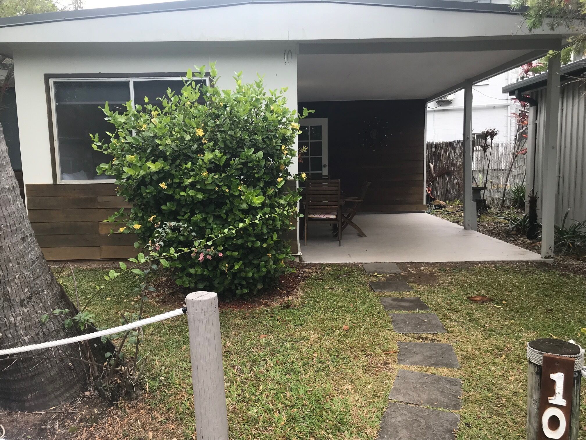 A modern house with a covered patio, a wooden bench, and a small garden area.