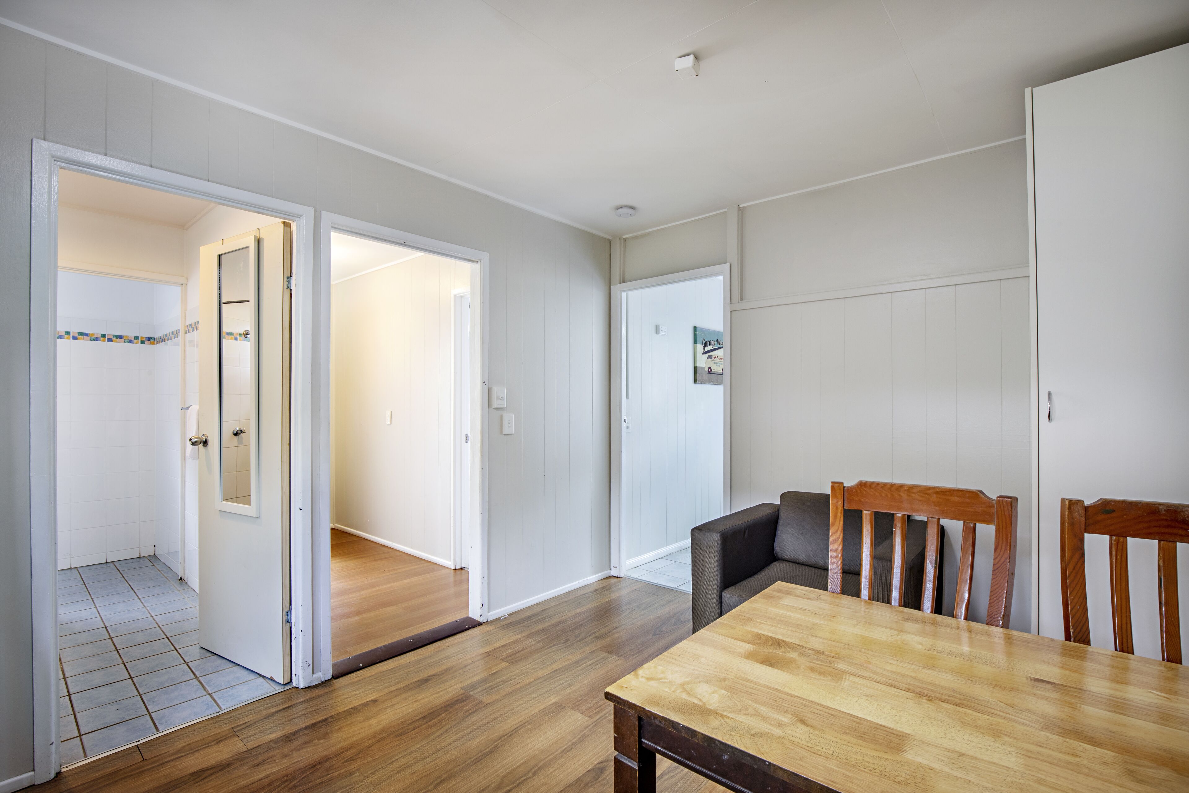 A room with a wooden dining table, a sofa, and a door leading to another room.
