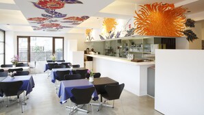 A dining area with tables and chairs, a kitchen area, and decorative ceiling artwork. - Kyoto Travelers Inn (Kyoto)