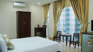 Una habitación de hotel con cama, escritorio, silla y un refrigerador pequeño.
