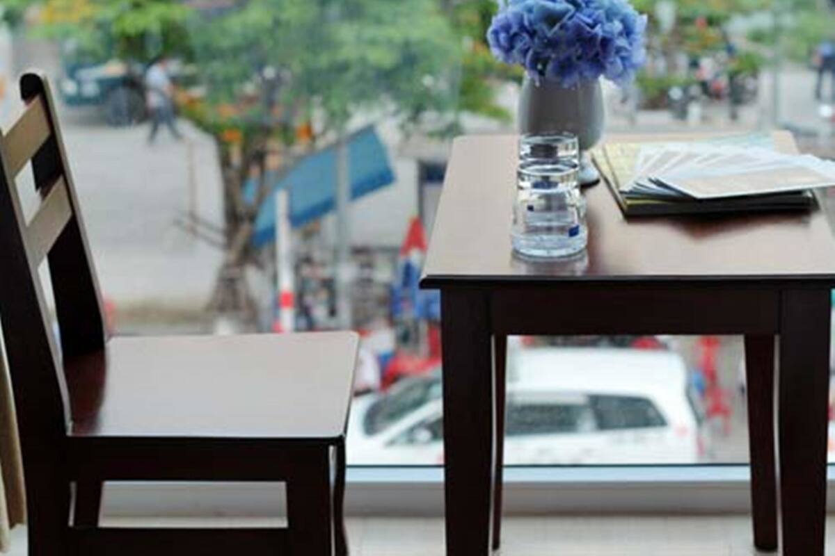 Una mesa con un jarrón de flores, una pila de documentos y un vaso de agua.
