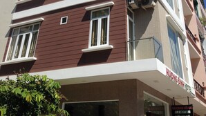 Un hotel de varios pisos con diseño moderno, que presenta una combinación de paredes exteriores rojas y beige, ventanas grandes y balcones.