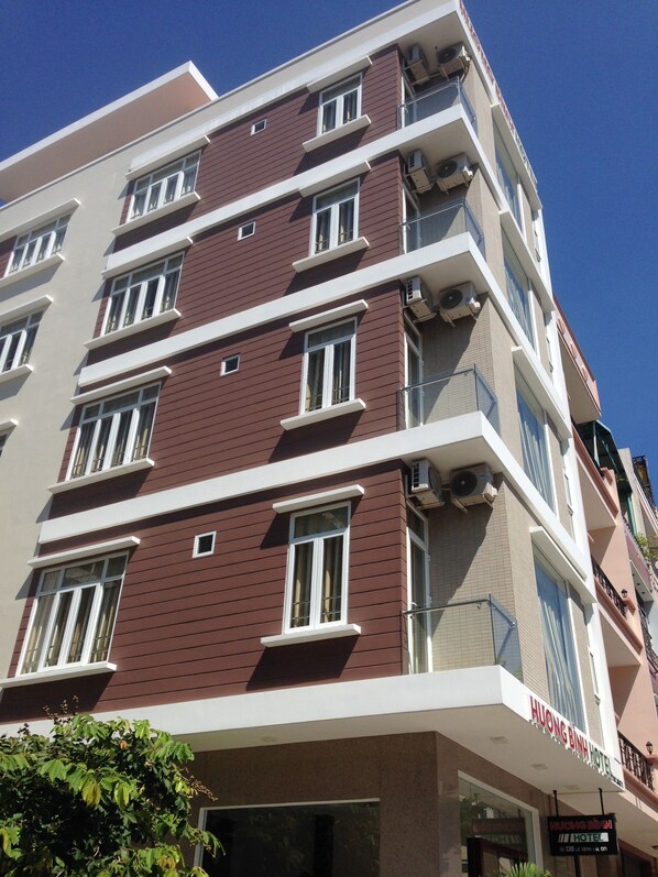 A multi-story hotel with a modern design, featuring a mix of red and beige exterior walls, large windows, and balconies.
