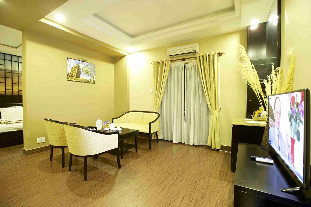 A hotel room with a dining area, a TV, and a window with curtains.