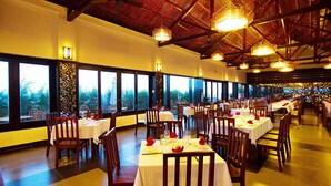 A restaurant with multiple tables and chairs, large windows, and a high ceiling with exposed beams. - Blue Bay Mui Ne Resort & Spa (Mui Ne)