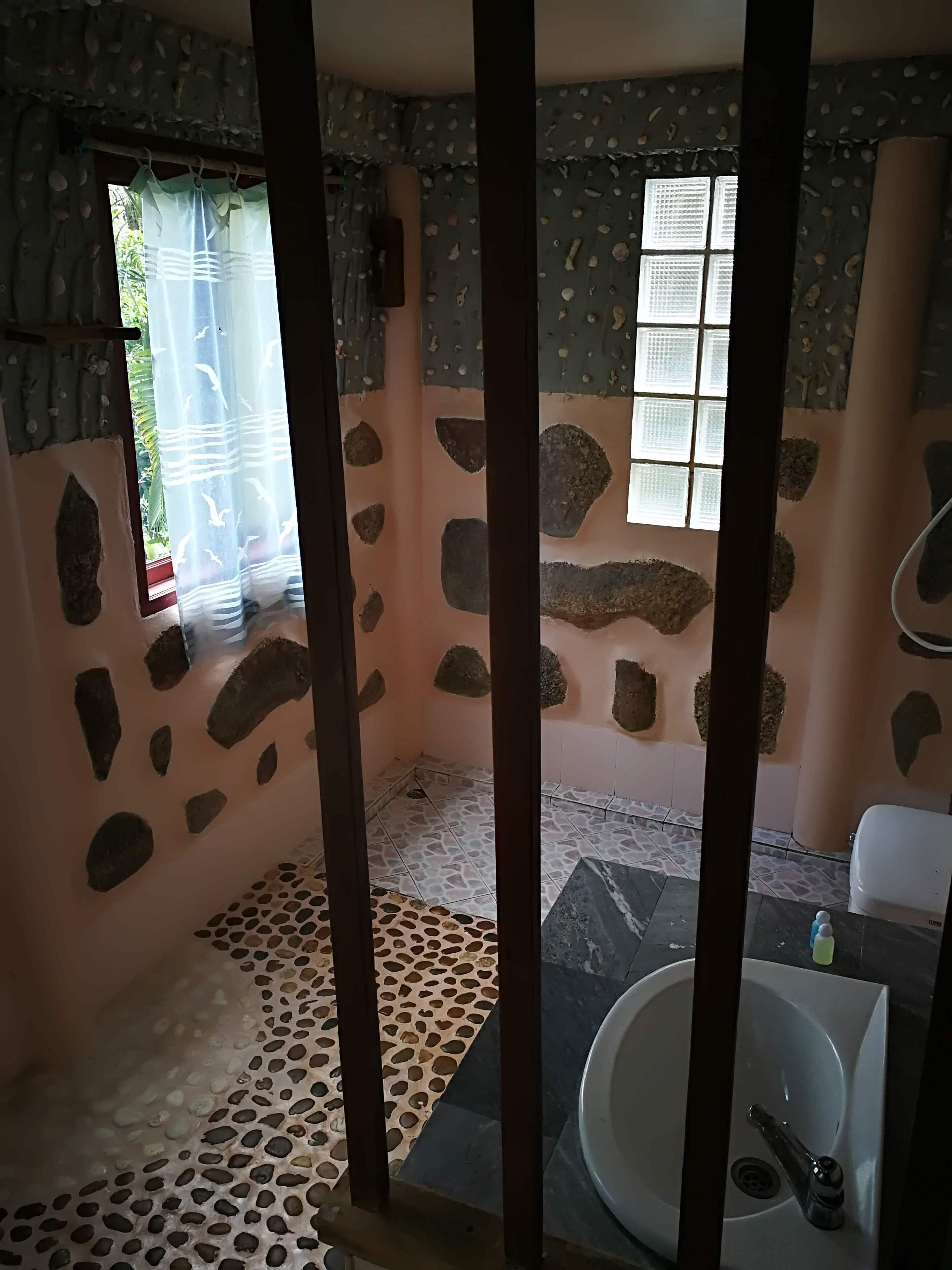 Un baño con paredes de piedra, una bañera y un lavabo.