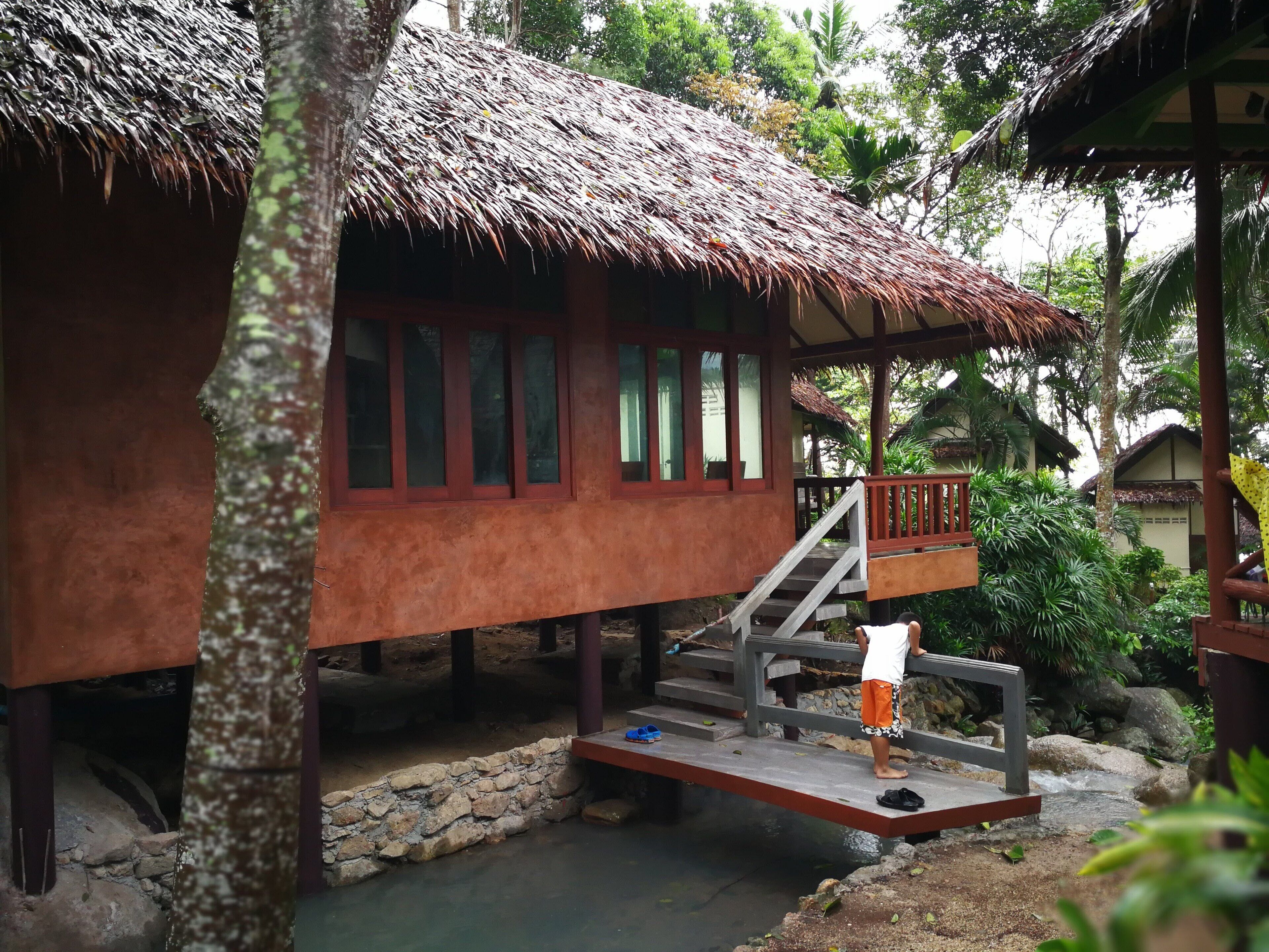 Eine Holzhütte mit einem Strohdach, einer Treppe und einem kleinen Pool.