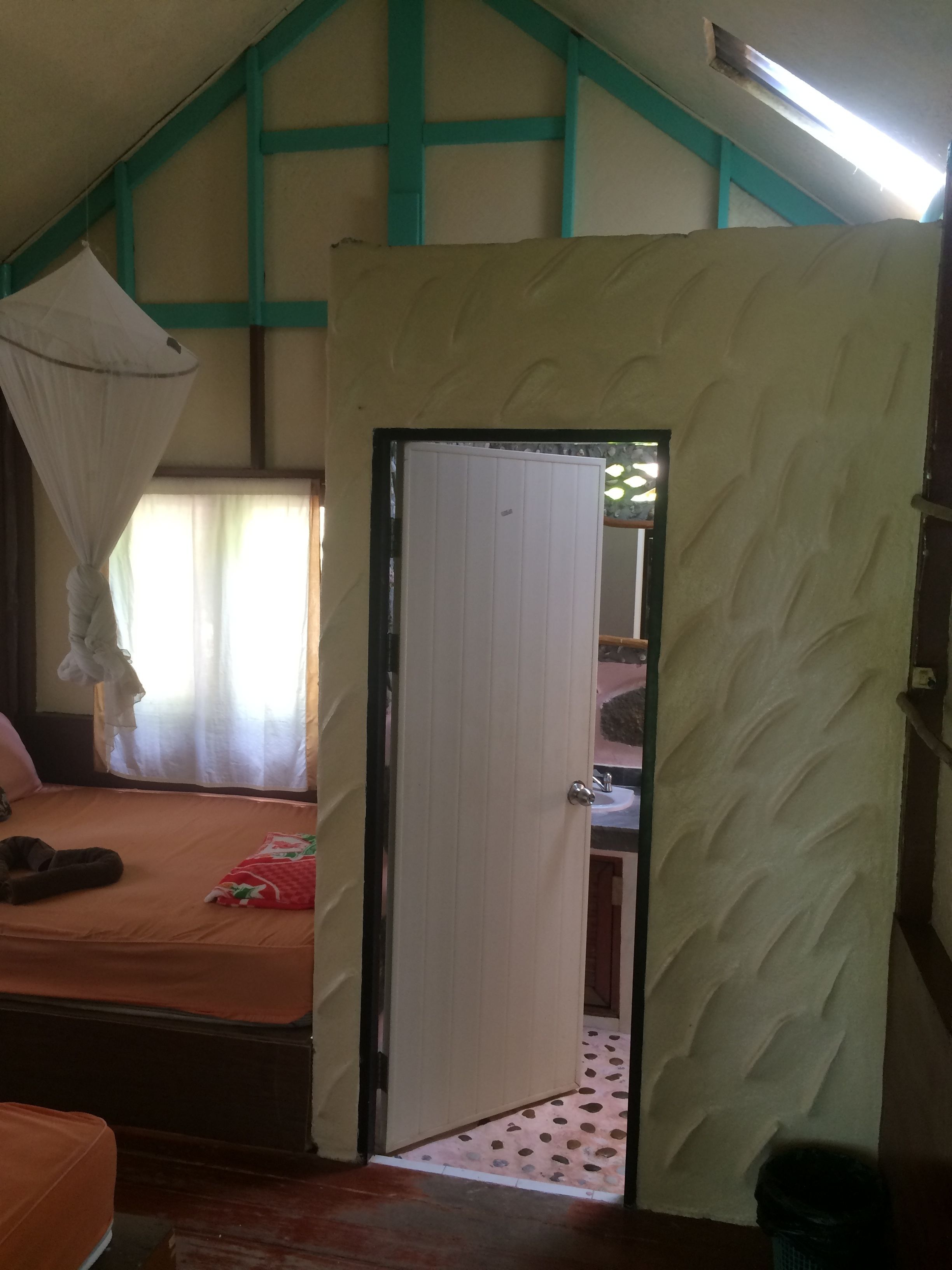 A room with a bed, a small table, and a door leading to another room.