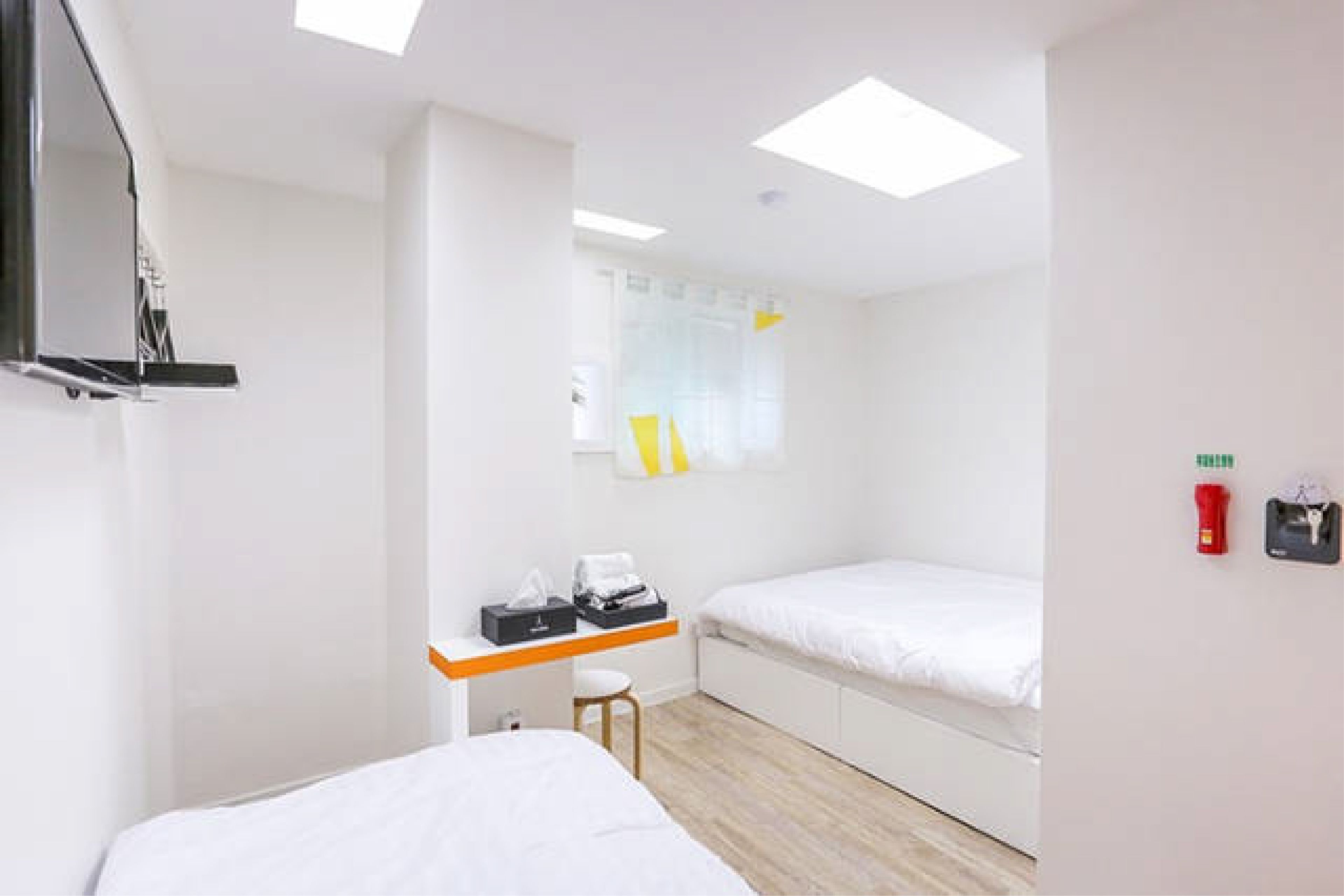 Une chambre d’hôtel moderne équipée d’un lit, d’un bureau avec une chaise, d’une petite table et d’une fenêtre avec des rideaux.