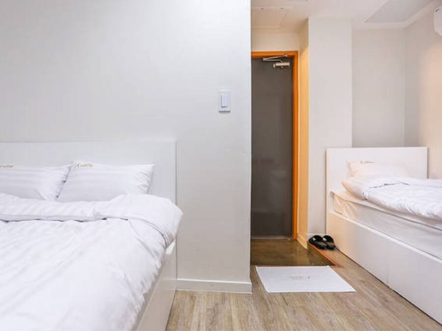 A modern hotel room with a large bed, a smaller bed, and a wooden floor.