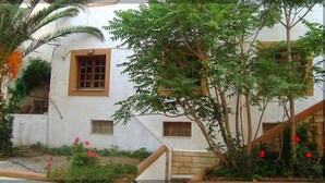 A building with a white exterior, multiple windows, and a staircase leading to the entrance. - Sunlight Hotel (Agios Vasileios)