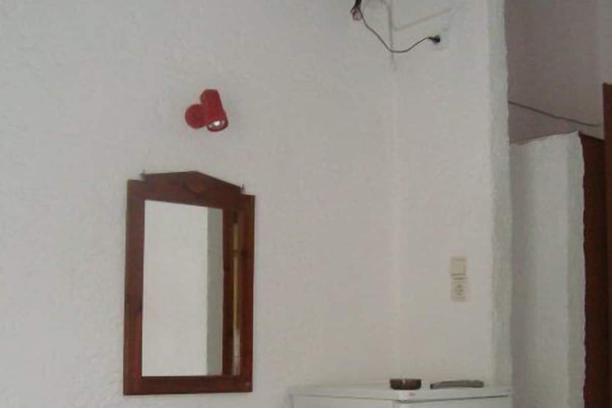 Un dormitorio con una cama, un escritorio de madera, un espejo y un refrigerador blanco.