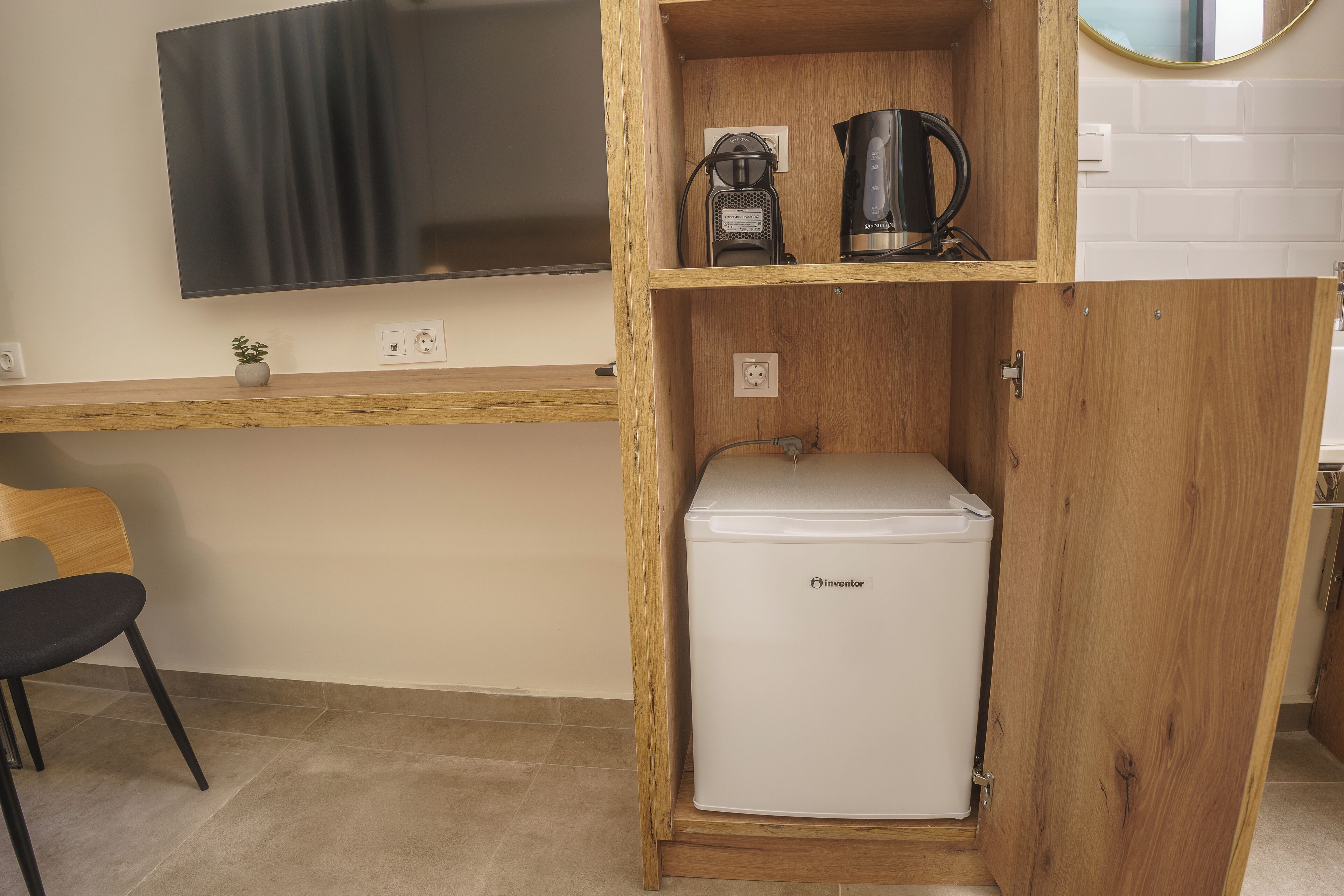 Una kitchenette compacta con un refrigerador blanco, una cafetera y una pequeña planta en la encimera.