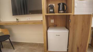 Una kitchenette compacta con un refrigerador blanco, una cafetera y una pequeña planta en la encimera.